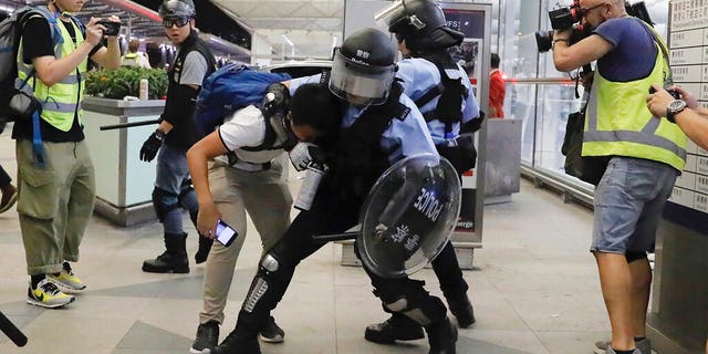 Policemen in riot gear arrest a protester during a demonstration at the airport in Hong Kong, Tuesday, Aug. 13, 2019. Chaos broke out at Hong Kong's airport as riot police moved into the terminal to confront protesters who shut down operations at the busy transport hub for two straight days.