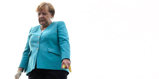 German Chancellor Angela Merkel stands next to a penguin after feeding it a treat, on the roof of the Ozeaneum in Stralsund, Germany, Tuesday, Aug. 13, 2019. 