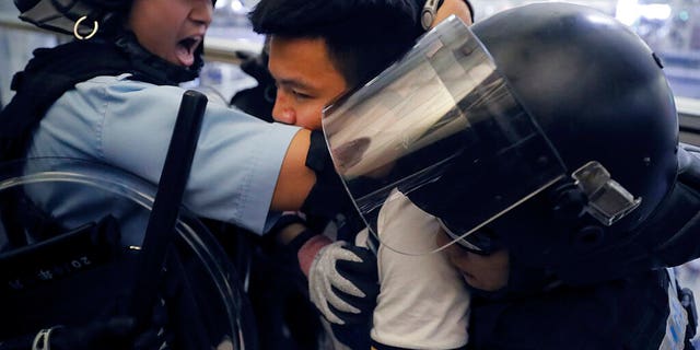 Policemen in riot gear arrest a protester during a demonstration at the airport in Hong Kong, Tuesday, Aug. 13, 2019.