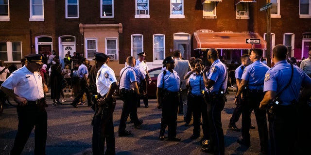 Officers gather for crowd control near a massive police presence set up outside a house as they investigate an active shooting situation, in Philadelphia, Wednesday, Aug. 14, 2019. (Associated Press)