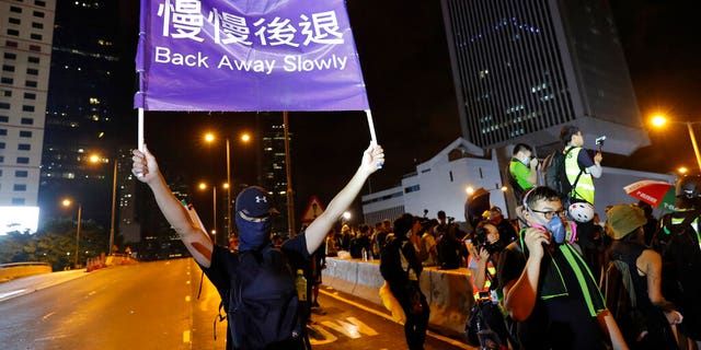 A demonstrator holding up a sign reading "Back away slowly" to encourage other demonstrators to leave, near the Chinese Liaison Office in Hong Kong on Sunday. (AP Photo/Vincent Thian)