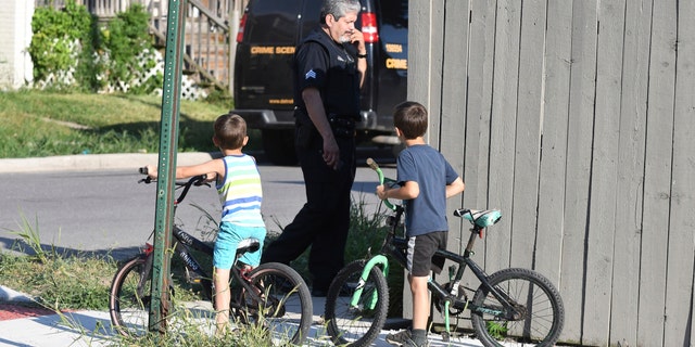 Two boys watch a Detroit detective investigate a deadly dog ​​attack on a girl who died in Detroit on Monday, August 19, 2019. 