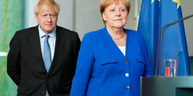 Germany's Chancellor Angela Merkel and British Prime Minister Boris Johnson arrive for a joint press conference, in Berlin, Wednesday, Aug. 21, 2019. German Chancellor Angela Merkel says she plans to discuss with UK Prime Minister Boris Johnson how Britain's exit from the European Union can be "as frictionless as possible."