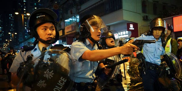 Policemen pull out their guns after a confrontation with demonstrators during a protest in Hong Kong on Sunday in the outlying Tsuen Wan district.