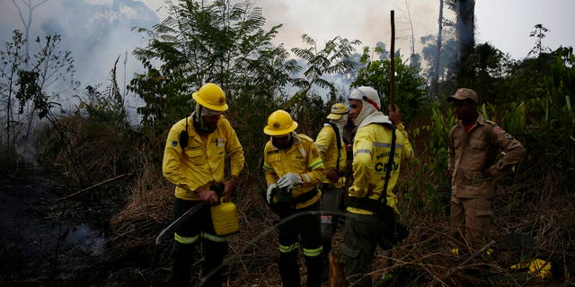 Firefighters rest briefly as they put out fires along the road to Jacunda National Forest, near the city of Porto Velho in the Vila Nova Samuel region which is part of Brazil's Amazon, Monday, Aug. 26, 2019.