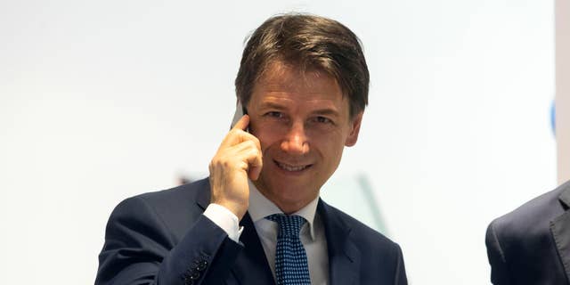 Italy's Prime Minister, Giuseppe Conte, talks at the phone inside a mobile phones shop in the center of Rome, Tuesday, Aug. 27, 2019.