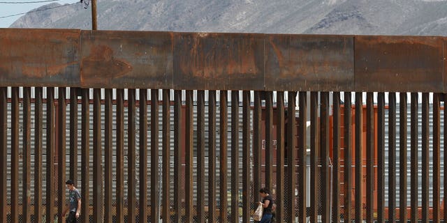 Three migrants who managed to evade the Mexican National Guard and cross the Rio Grande onto U.S. territory walked along a border wall set back from the geographical border, in El Paso, Texas, as seen from Ciudad Juarez, Mexico. (AP Photo/Christian Chavez, File)