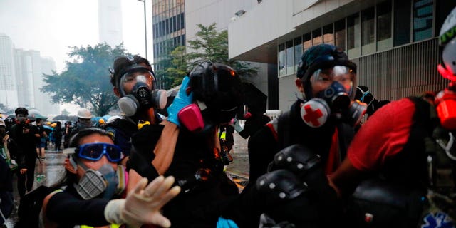 Protestors carry an injured to safety in Hong Kong, Saturday, Aug. 31, 2019. Many of the protesters outside Hong Kong government headquarters have retreated as large contingents of police arrive on the streets in what looks like preparation for a clearing operation. Police were using tear gas Saturday to drive back remaining protesters.