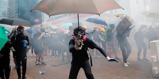 Protestors run for cover from tear gas shells in Hong Kong, Saturday, Aug. 31, 2019. Many of the protesters outside Hong Kong government headquarters have retreated as large contingents of police arrive on the streets in what looks like preparation for a clearing operation. Police were using tear gas Saturday to drive back remaining protesters. 