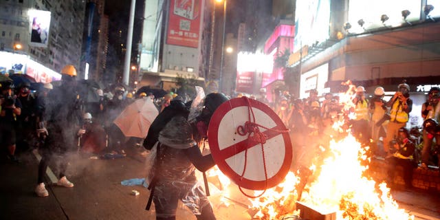 A protestor uses a shield to cover himself as he faces policemen in Hong Kong, Saturday, Aug. 31, 2019. Protesters and police are standing off in Hong Kong on a street that runs through the bustling Causeway Bay shopping district. (AP Photo/Jae C. Hong)