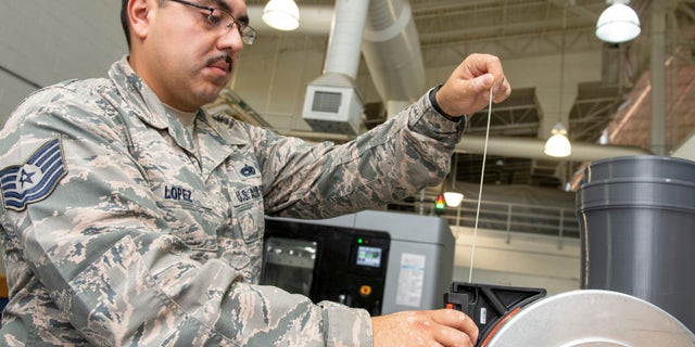 U.S. Air Force Tech. Sgt. Rogelio Lopez, 60th Maintenance Squadron assistant aircraft metals technology section chief, loads Ultem 9085 material into a canister for use in the Stratasys F900 three-dimensional printer Aug. 15, 2019, Travis Air Force Base, California.