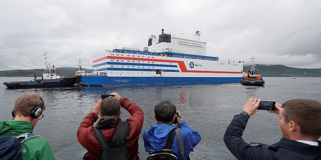 People take pictures of Russia's floating nuclear power plant Akademik Lomonosov as it leaves port Friday in Murmansk.