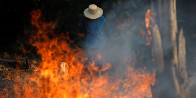 A man works in a burning tract of Amazon jungle as it is being cleared by loggers and farmers in Iranduba, Amazonas state, Brazil August 20, 2019.
