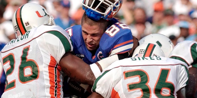FILE - In this Sept. 7, 2002 file photo, Florida's tight end Aaron Walker, (82) loses his helmet as he is hit by Miami defenders Sean Taylor (26) and Maurice Sikes (36) during the first quarter of a NCAA college football game, in Gainesville, Fla. (AP Photo/Phelan Ebenhack, File)