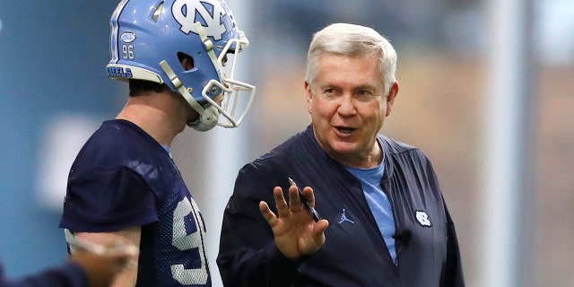 FILE - In this March 3, 2019, file photo, North Carolina head coach Mack Brown talks with Cooper Graham (96) during UNC's first spring football practice, in Chapel Hill, N.C. Brown is savoring his return to coaching in a second stint with the Tar Heels. (Ethan Hyman/The News & Observer via AP, File)