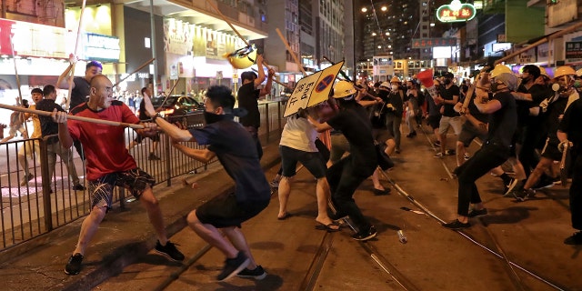 In this Monday, Aug. 5, 2019, photo, protesters wearing black shirt, right, fight with a group of men wielding wooden poles on a street during the anti-extradition bill protest at a neighborhood in Hong Kong.