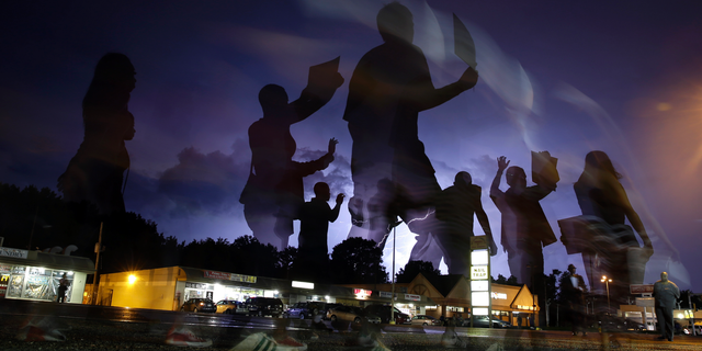 FILE - In this Aug. 20, 2014, file photo, protesters march in the street as lightning flashes in the distance in Ferguson, Mo. Michael Brown's death on Aug. 9, 2014, at the hands of a white Missouri police officer stands as a seismic moment of race relations in America. The fledgling Black Lives Matter movement found its voice, police departments fell under intense scrutiny, progressive prosecutors were elected and court policies revised. (AP Photo/Jeff Roberson, File)