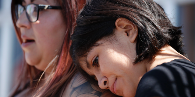 Eleven-year-old Leilani Hebben puts her head on her mother Anabel Hebben's shoulder as they visit the scene of a mass shooting at a shopping complex Sunday, Aug. 4, 2019, in El Paso, Texas. (AP Photo/John Locher)