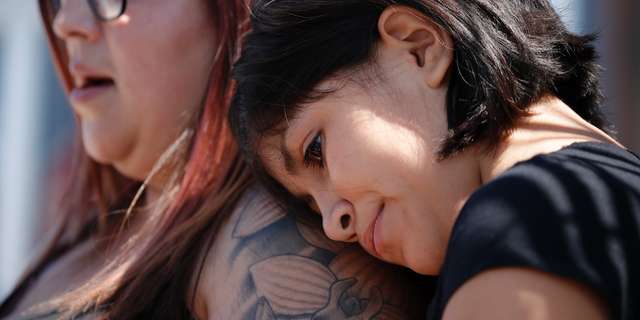 Eleven-year-old Leilani Hebben puts her head on her mother Anabel Hebben's shoulder as they visit the scene of a mass shooting at a shopping complex Sunday, Aug. 4, 2019, in El Paso, Texas. (AP Photo/John Locher)