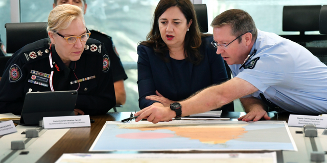 In this March 19, 2019, photo, Queensland Fire and Emergency Services Commissioner, Katarina Carroll (left), Queensland Premier Annastacia Palaszczuk (center) and Queensland Police Deputy Commissioner Bob Gee (right) are seen during a meeting of the Queensland Disaster Management Committee discussing the approaching cyclone at the Emergency Services Complex in Brisbane. Australia is evacuating about 2,000 people from part of northern Australia ahead of powerful Cyclone Trevor expected to hit on Saturday.