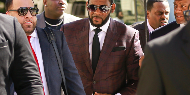 R. Kelly, center, arrives at the Leighton Criminal Court building for an arraignment on sex-related felonies in Chicago onÂ June 26, 2019. (AP Photo/Amr Alfiky, File)