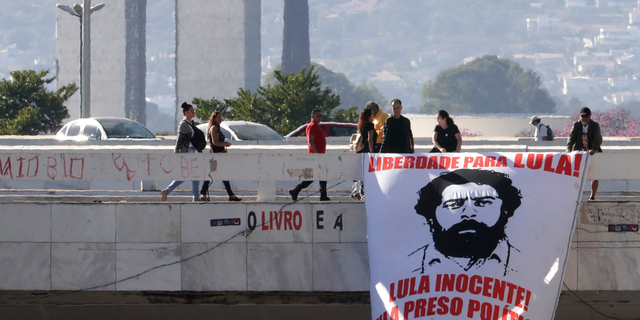 Supporters of imprisoned former President of Brazil Luiz Inacio Lula da Silva, place a banner with the image of the former president and with text written in Portuguese that reads "Freedom for Lula, "Lula is innocent, Lula is a political prisoner," at a bus station in Brasilia, Brazil, Thursday, Aug. 1, 2019. (AP Photo/Eraldo Peres)