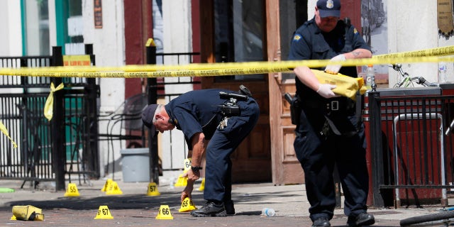 Authorities retrieve evidence markers at the scene of a mass shooting, Sunday, Aug. 4, 2019, in Dayton, Ohio.