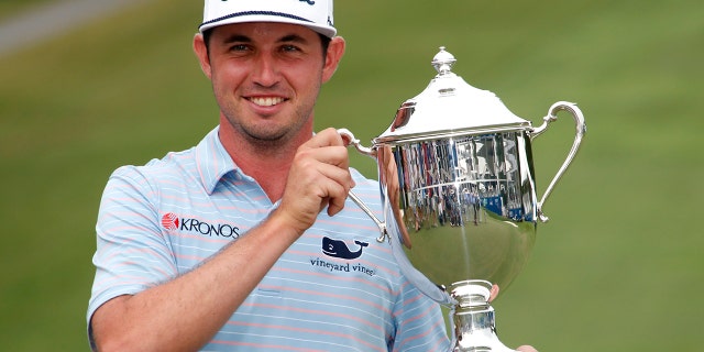 J. T. Poston holds the trophy after he won the Wyndham Championship golf tournament at Sedgefield Country Club in Greensboro, N.C., Sunday, Aug. 4, 2019. (AP Photo/Chris Seward)