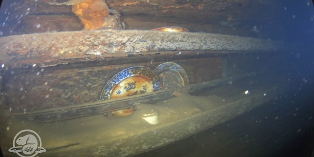 Plates and other artifacts on shelves next to a mess table where lower ranking crew members of HMS Terror would have taken their meals.