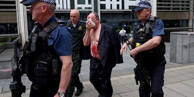 An injured man is helped by a medic and police officers outside the Home Office in London, Britain August 15, 2019.