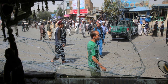 Afghans are seen through a shattered glass of a transport bus broken after an explosion in Kabul, Afghanistan, Wednesday, Aug. 7, 2019.