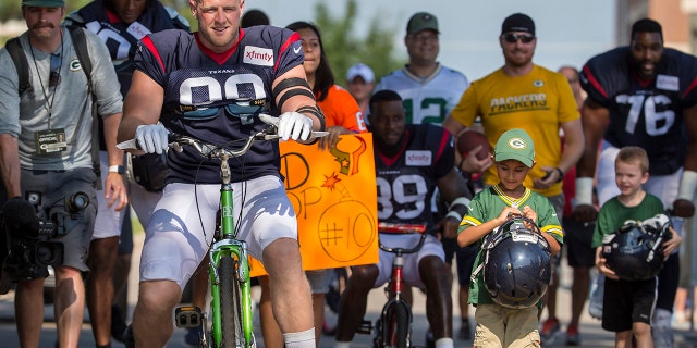 Houston Texans' J.J. Watt rides a bike to a joint NFL football practice between the Texans and the Green Bay Packers Monday, Aug 5, 2019, in Green Bay, Wis. (AP Photo/Mike Roemer)