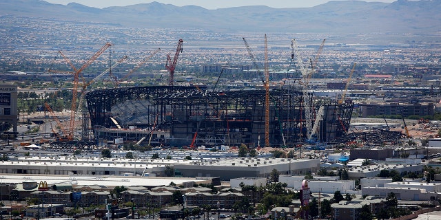 FILE - In this June 4, 2019, file photo, construction cranes surround the football stadium under construction in Las Vegas. The $1.9 billion stadium being built in Las Vegas for the relocated NFL Raiders team is being named for Allegiant Travel Co. Officials made the announcement Monday, Aug. 5, 2019, during a ceremony marking installation of the final steel beam for the roof of the 65,000-seat indoor stadium just off the Las Vegas Strip. (AP Photo/John Locher, File)