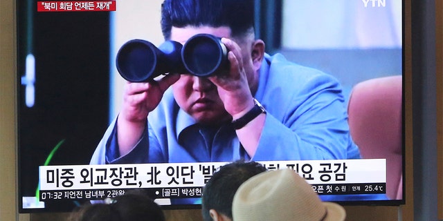 People stand by a TV screen showing file footage of North Korean leader Kim Jong Un, at the Seoul Railway Station, Aug. 2, 2019.
