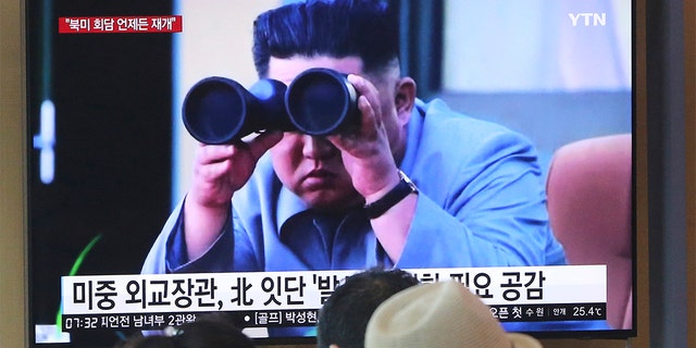 People stand next to a television screen showing footage of North Korean leader Kim Jong Un, at Seoul train station, Aug.2, 2019.