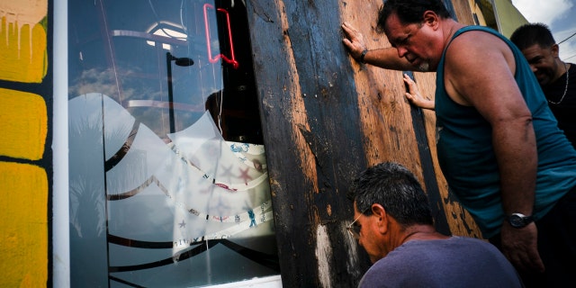 Men board up a shop's windows ahead of the arrival of Tropical Storm Dorian in Boqueron, Puerto Rico, Tuesday, Aug. 27, 2019.