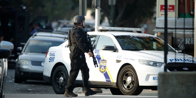 A police officer patrols the block near a house as they investigate an active shooting situation, Wednesday, Aug. 14, 2019, in the Nicetown neighborhood of Philadelphia.