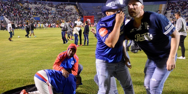 Spectators react from tear gas after three people died in riots before a soccer match when the fans attacked a bus carrying one of the teams, at the National Stadium in Tegucigalpa, Honduras August 17, 2019.