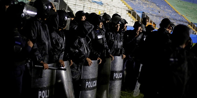 Police officers keep watch after three people died in riots before a soccer match in Tegucigalpa, Honduras.