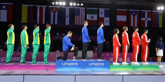 Gold medalist Race Imboden of United States takes a knee during the National Anthem Ceremony in the podium of Fencing Men's Foil Team Gold Medal Match Match on Day 14 of Lima 2019 Pan American Games at Fencing Pavilion of Lima Convention Center on August 09, 2019 in Lima, Peru. (Photo by Leonardo Fernandez/Getty Images)