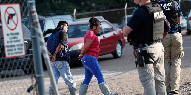 Two people are taken into custody at a Koch Foods Inc. plant in Morton, Miss., on Wednesday, Aug. 7, 2019. U.S. immigration officials raided several Mississippi food processing plants on Wednesday and signaled that the early-morning strikes were part of a large-scale operation targeting owners as well as employees.