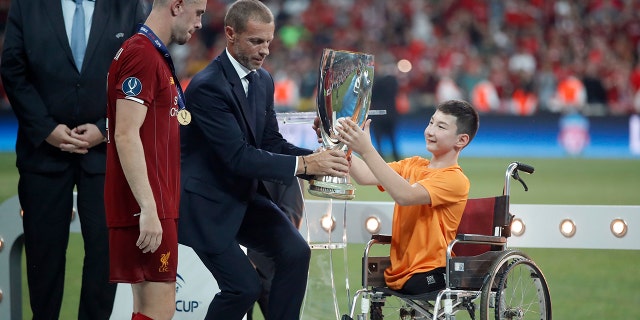 UEFA President Aleksander Ceferin and Ali Turganbekov, from Kazakhstan, right, hand the trophy to Liverpool's team captain Jordan Henderson after Liverpool won the UEFA Super Cup soccer match between Liverpool and Chelsea, in Besiktas Park, in Istanbul, Thursday, Aug. 15, 2019. Liverpool won 5-4 in a penalty shootout after the game ended tied 2-2. (AP Photo/Thanassis Stavrakis)