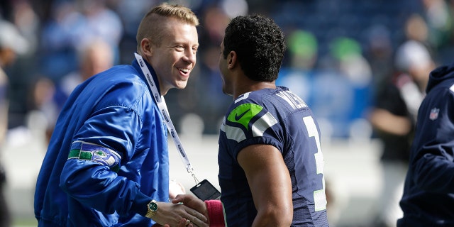 FILE - In this Oct. 13, 2013, file photo, Seattle hip hop and rap singer Macklemore, left, greets Seattle Seahawks quarterback Russell Wilson before an NFL football game between the Seahawks and Tennessee Titans in Seattle. The MLS soccer Seattle Sounders team announced Tuesday, Aug. 13, 2019, that they are adding Macklemore and Wilson to club's ownership group, along with several others as Hollywood producer Joe Roth leaves the franchise.(AP Photo/Elaine Thompson, File)