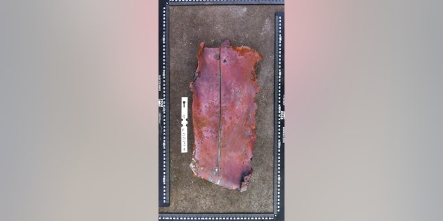 Fragment of a metal composite plate excavated on Sept. 9, 2018. It consists of a layer of copper, backed by a layer of lead. Historical information indicates that the stern post and rudder of Dutch East India Company ships like 'Haarlem' used plates such as this. (©AIMURE/Bruno Werz)