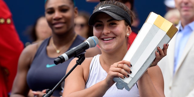 Canada's Bianca Andreescu holds the winner's trophy as Serena Williams of the USA looks on after Williams had to retire from the final of the Rogers Cup tennis tournament in Toronto on Sunday, Aug. 11, 2019. (Frank Gunn/The Canadian Press via AP)
