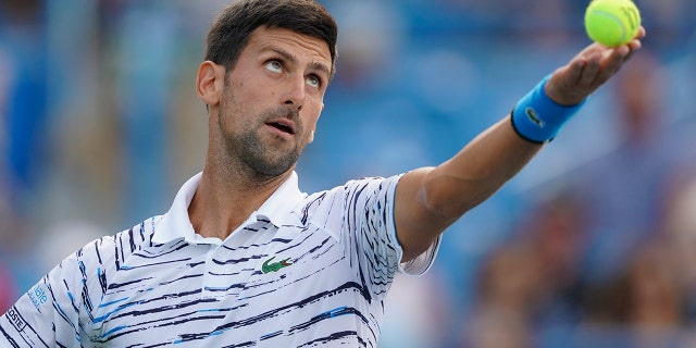 Novak Djokovic, of Serbia, tosses the ball on a serve to Daniil Medvedev, of Russia, during the Western & Southern Open tennis tournament Saturday, Aug. 17, 2019, in Mason, Ohio. (AP Photo/John Minchillo)