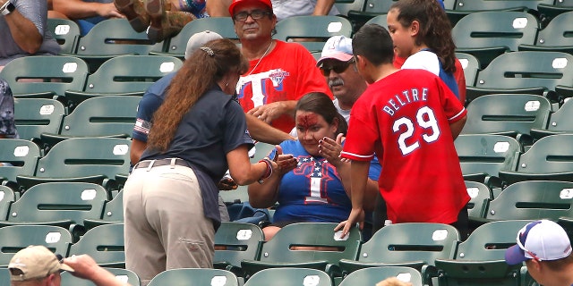 A fan reacts after being stuck in the forehead by a foul ball off the bat of Willie Calhoun #5 of the Texas Rangers as the Rangers play the Detroit Tigers during the first inning at Globe Life Park in Arlington on August 4, 2019 in Arlington, Texas. (Photo by Ron Jenkins/Getty Images)