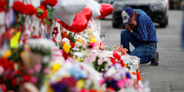 A man cries beside a cross at a makeshift memorial near the scene of a mass shooting at a shopping complex Tuesday, Aug. 6, 2019, in El Paso, Texas. (AP Photo/John Locher)