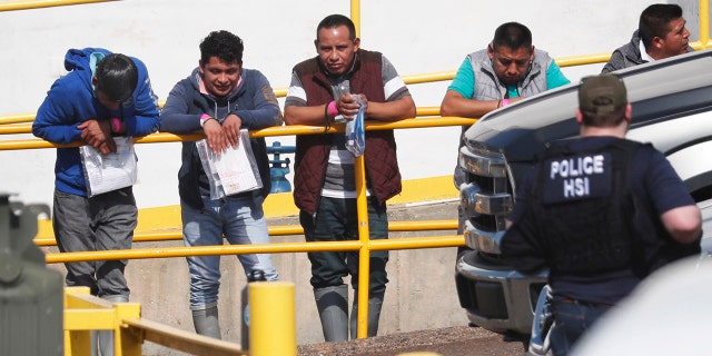 Handcuffed workers await transportation to a processing center following a raid by U.S. immigration officials at Koch Foods Inc., plant in Morton, Miss. U.S. immigration officials raided several Mississippi food processing plants on Wednesday and signaled that the early-morning strikes were part of a large-scale operation targeting owners as well as employees. (AP Photo/Rogelio V. Solis)