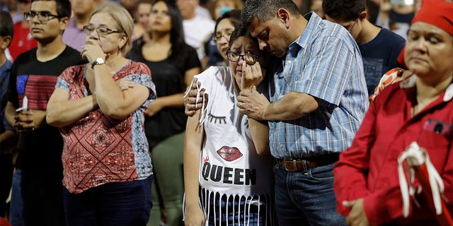 People comfort each other during a vigil for victims of Saturday's mass shooting at a shopping complex Sunday, Aug. 4, 2019, in El Paso, Texas.